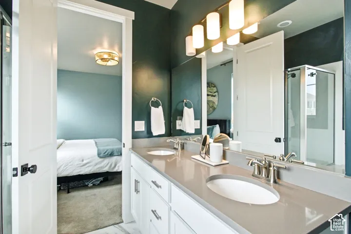 Dual vanity with undermount sinks, brushed nickel fixtures, a full-width mirror, and a glass-enclosed shower