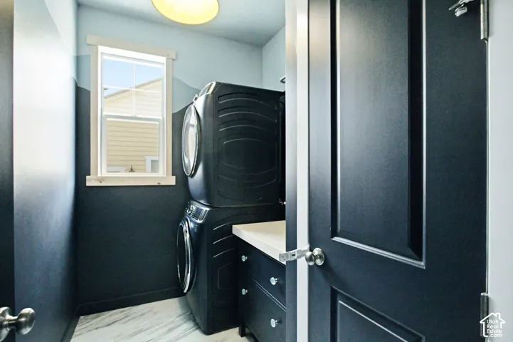 Laundry area featuring a window with natural wood trim, a built-in countertop, and white marble-look flooring