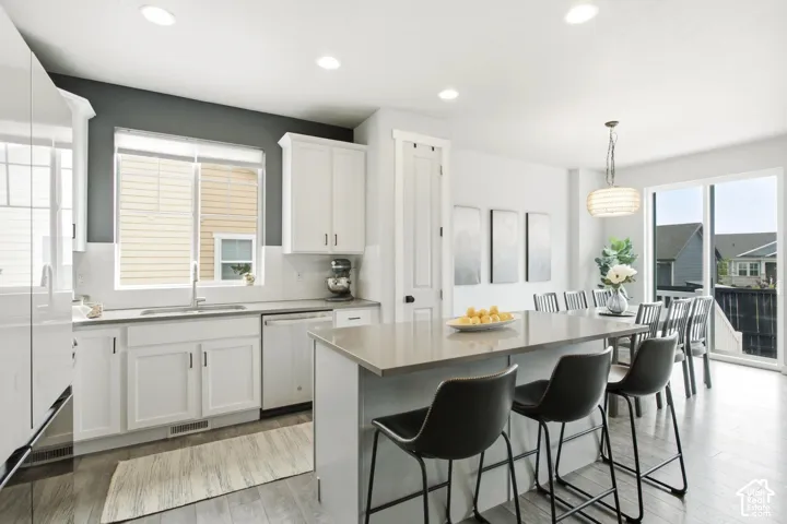 Open-concept kitchen with recessed lighting, light wood-finish flooring, a kitchen island with seating, white cabinetry, and sliding glass patio doors