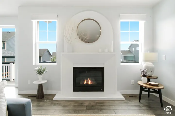Fireplace with an arched mantel, wood-finish flooring, and multiple windows with roller shades