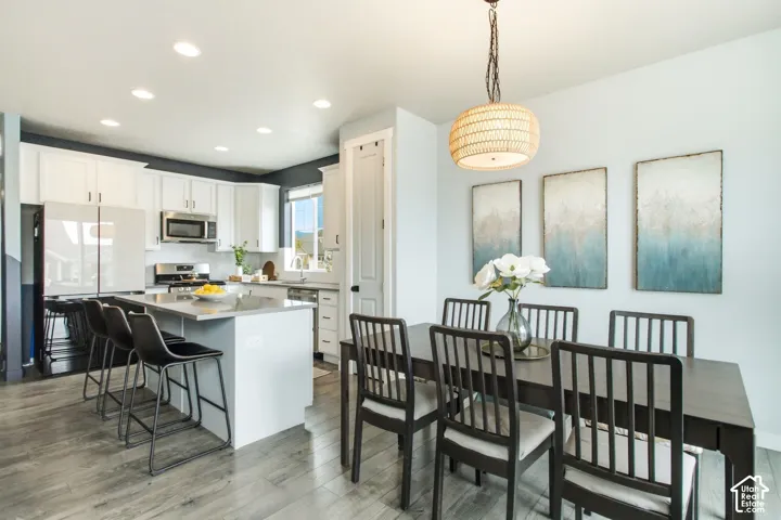 Open-concept kitchen featuring white cabinetry, stainless steel appliances, and a central island with bar seating