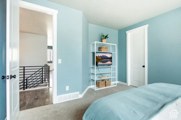 Carpeted flooring, light blue wall paint, white trim, and a white door with black hardware