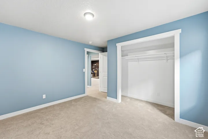 Plush carpet flooring, light blue wall finishes, white trim, and a built-in closet with shelving and hanging rods