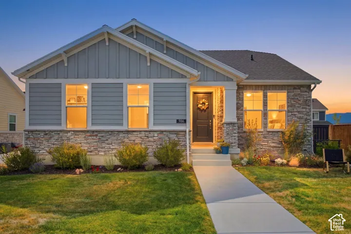 Stone veneer exterior with siding accents, a gabled roofline, a concrete walkway, and landscaped garden beds