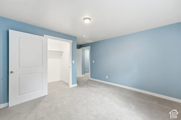 Plush carpet flooring, light blue wall finishes, white trim, recessed lighting, and a closet with shelving and hanging rod