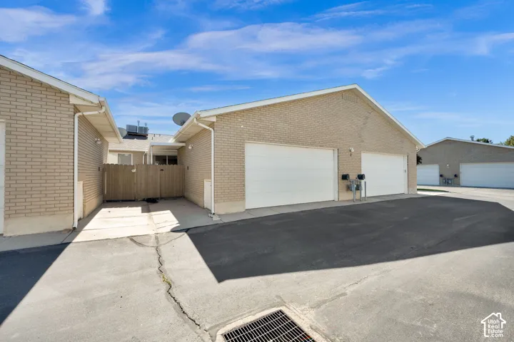 Brick exterior with white garage doors and a paved driveway