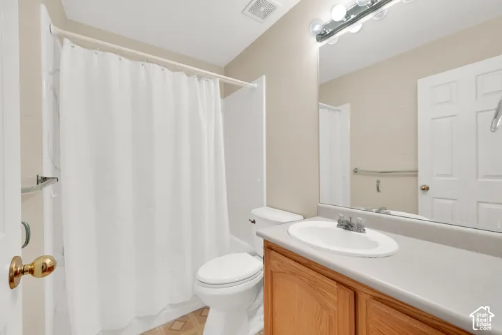 Bathroom featuring a built-in wood-finish vanity, integrated sink, and full-width mirror with overhead lighting