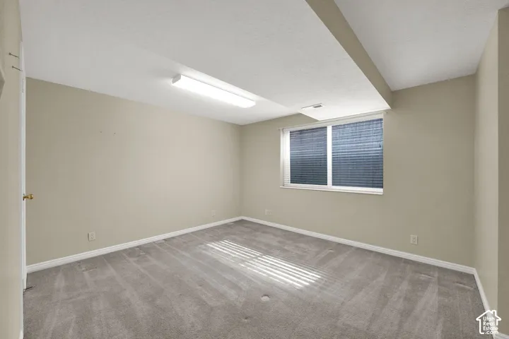 Bright, versatile room featuring abundant natural light from dual windows with integrated blinds, recessed ceiling lighting, and neutral carpeting throughout
