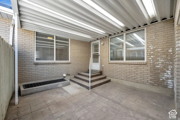 Covered patio area featuring a stamped concrete surface, light brick exterior, and multi-pane windows