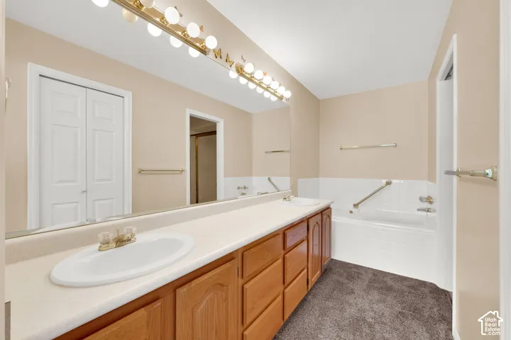 Dual vanity with wood-finish cabinetry, broad countertop, and integrated sinks