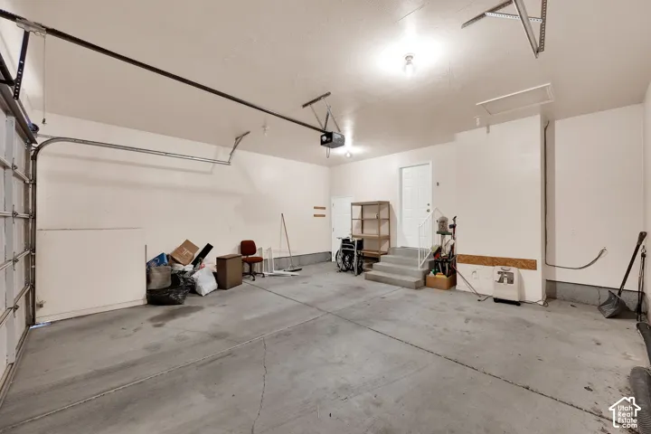 Concrete flooring, overhead lighting, interior access door, garage door, built-in shelving