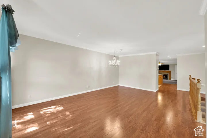 Wood-finish flooring, crown molding, a built-in chandelier, and a wood banister