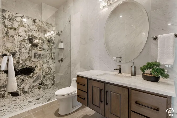 Glass-enclosed shower with a striking natural stone wall and herringbone tile floor