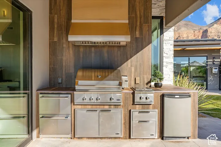 Outdoor kitchen featuring stainless steel grill, range hood, and integrated appliances