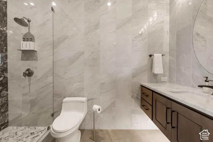 Glass-enclosed shower with a rainfall showerhead, full wall tile, and a floating vanity with an integrated sink