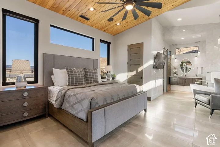 Vaulted wood-paneled ceiling with a ceiling fan, multiple windows with dark framing, large format tile flooring, and a sliding barn door