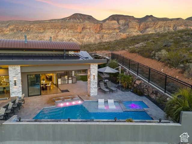 Expansive backyard with a rectangular pool, integrated spa, and an outdoor kitchen area