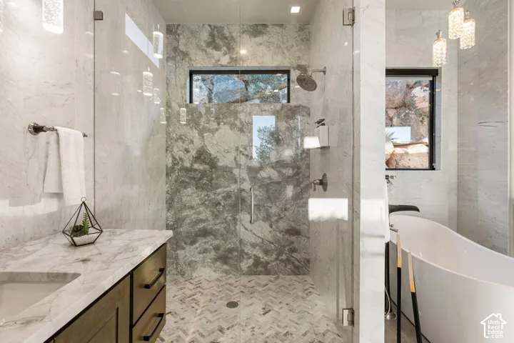 Glass-enclosed shower with a rainfall showerhead, herringbone tile flooring, and stone wall tiling