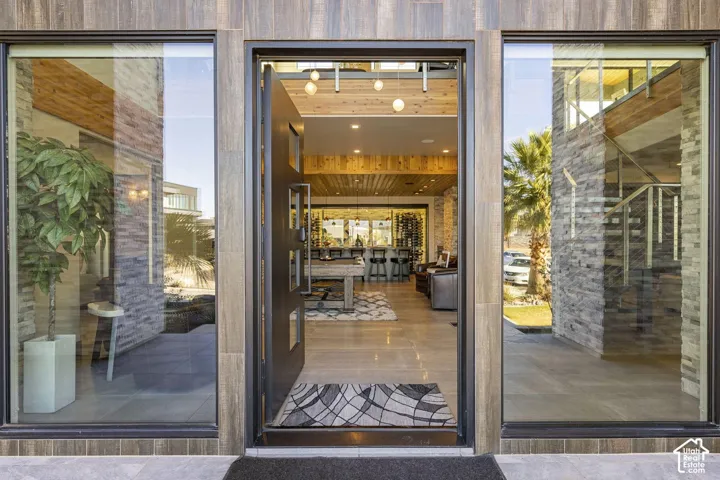Modern entry with a pivoting door, large glass panels, wood-finish siding, and stacked stone accents
