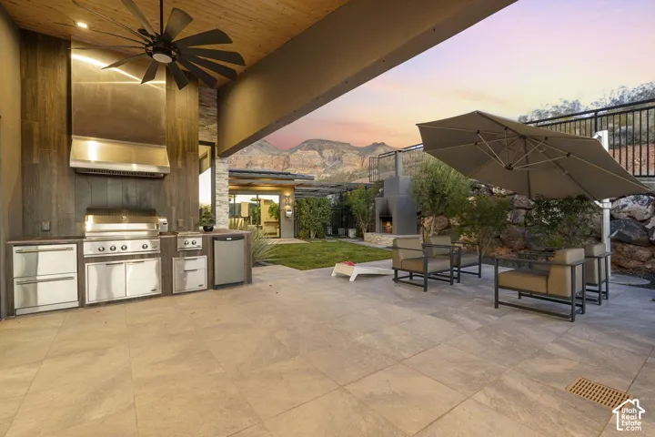 Outdoor kitchen featuring a built-in grill, stainless steel appliances, and integrated hood vent