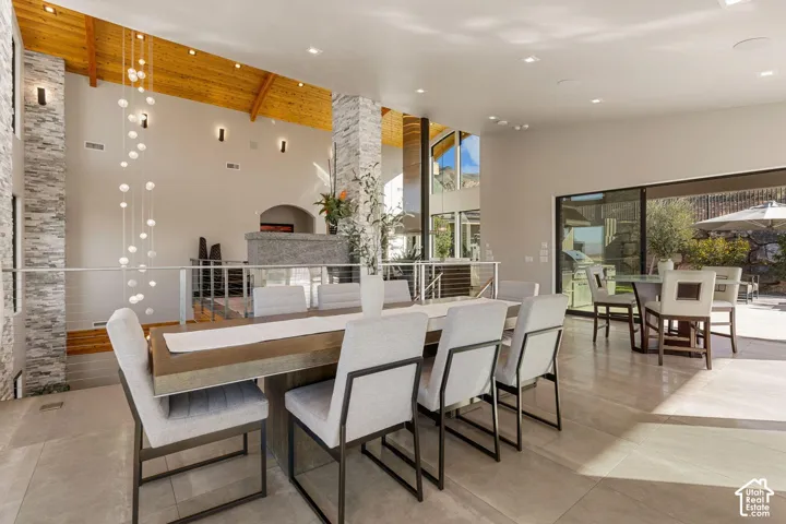 Vaulted wood-paneled ceiling, floor-to-ceiling stone-clad pillars, expansive glass sliding doors, and large format tile flooring