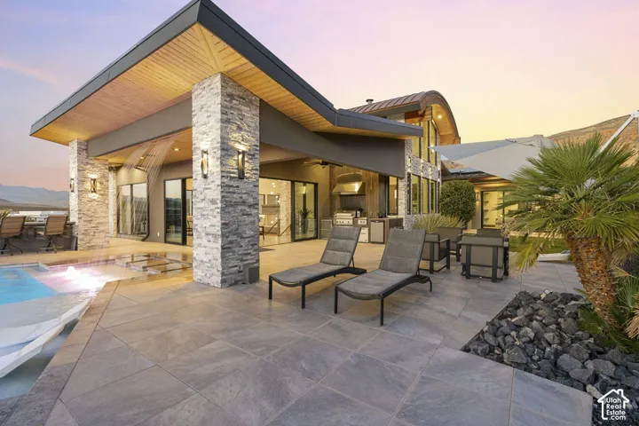 Expansive patio with large format tile flooring, a built-in outdoor kitchen, recessed lighting, and a water feature