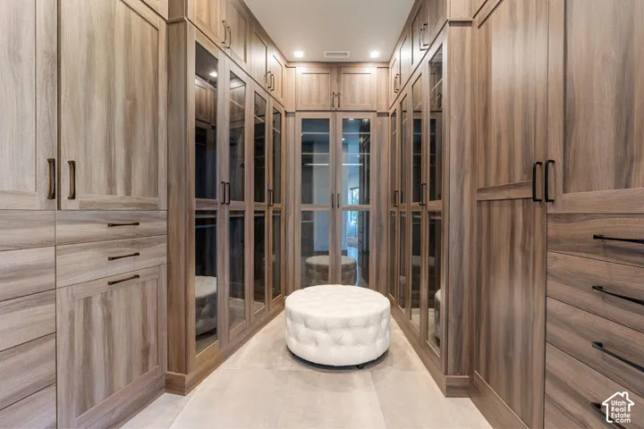 Custom closet system featuring wood-finish cabinetry, integrated glass-front doors, built-in drawers, and recessed lighting