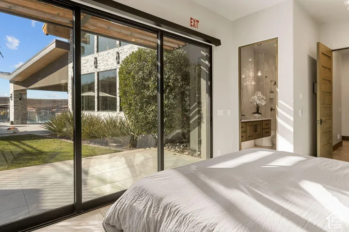 Full-height sliding glass doors, light-toned tile flooring, open-concept bathroom access, wood-finish vanity with countertop, and modern wood-finish interior door