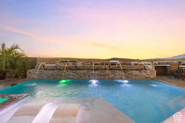 Swimming pool with integrated fountains, a stone-clad water feature, and an exterior patio space