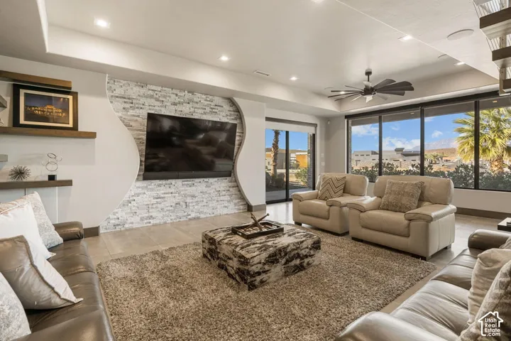 Living space featuring large format tile flooring, a decorative stone accent wall, recessed lighting, and a ceiling fan