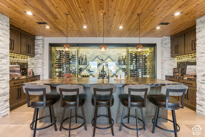Custom wine cellar, wood-paneled ceiling, stone accent walls, integrated bar, and built-in cabinetry