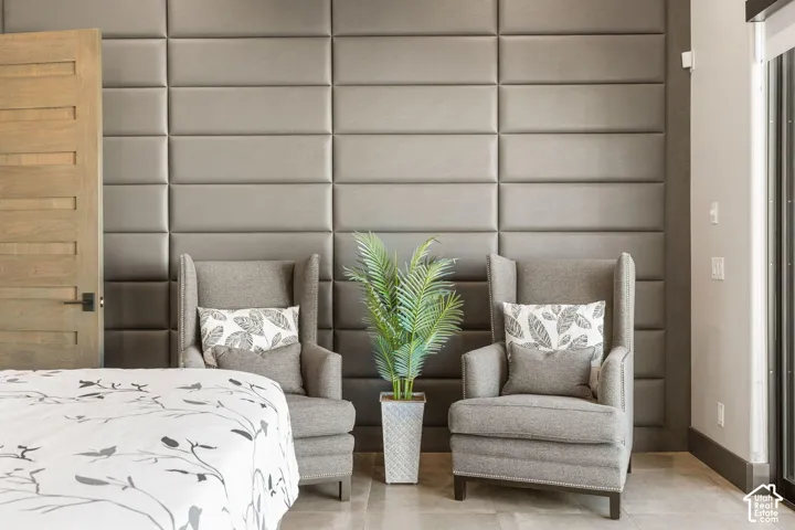 Primary Bedroom Suite featuring an upholstered wall treatment with geometric paneling, hardwood flooring, and two coordinating upholstered armchairs positioned for comfortable seating