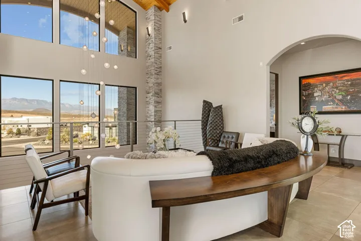 Two-story great room with soaring ceiling, expansive window array, stone veneer column, and arched entryway