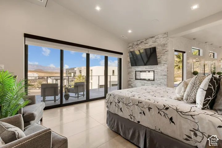Expansive sliding glass doors to outdoor patio, integrated linear fireplace, stone accent wall, recessed lighting, and tile flooring