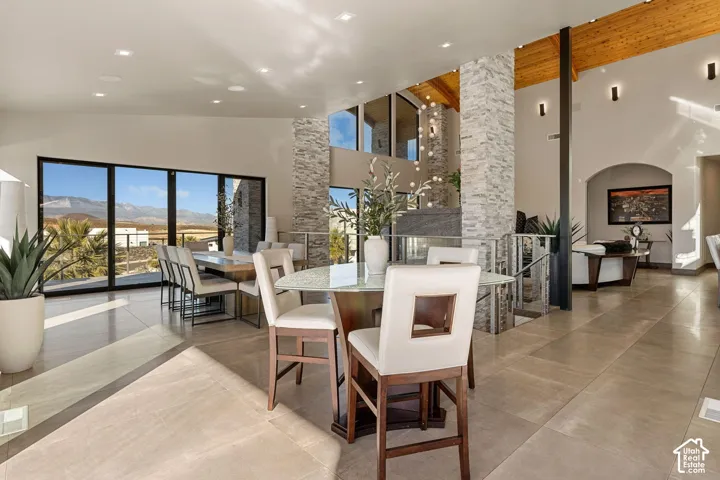 Expansive tile flooring throughout, featuring a stone-clad accent wall, vaulted wood-paneled ceilings, and large format windows