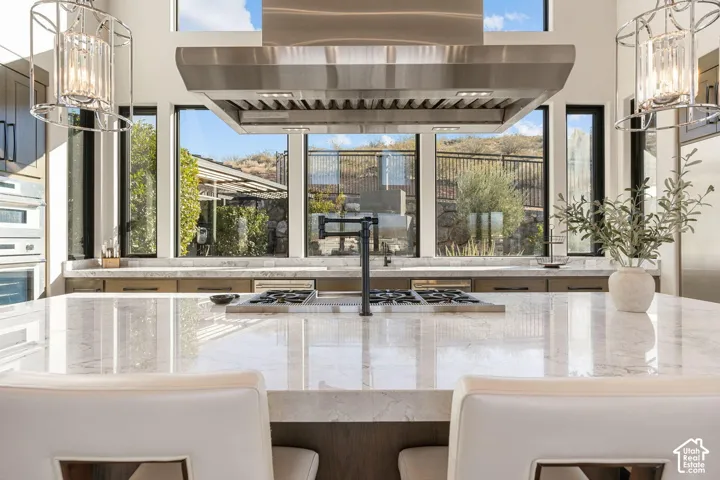 Expansive kitchen island with a light-toned countertop, integrated cooktop, and pot filler