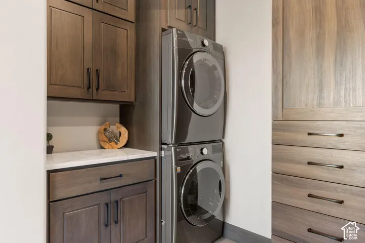 Integrated laundry appliances, wood-finish cabinetry, white countertop, and built-in drawers