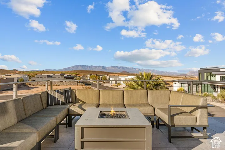 Rooftop patio featuring a built-in fire pit, mountain backdrop, and expansive outdoor seating
