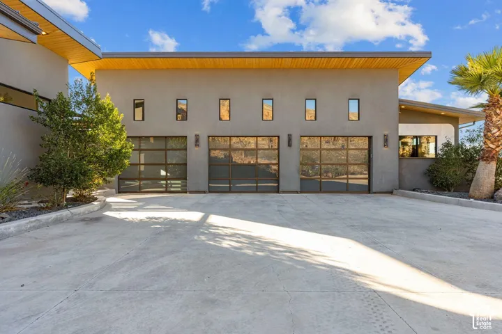 Modern exterior featuring a stucco finish, three transparent garage doors, and linear windows