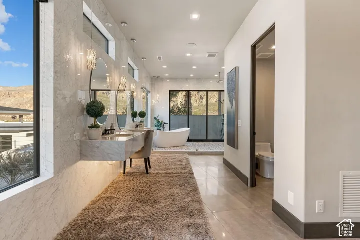 Spa-inspired primary bathroom featuring dual vanities with quartz countertops, vessel sinks, and polished chrome fixtures, complemented by recessed ceiling lighting, large-format tile flooring, and frameless glass-enclosed shower enclosure with tile surro