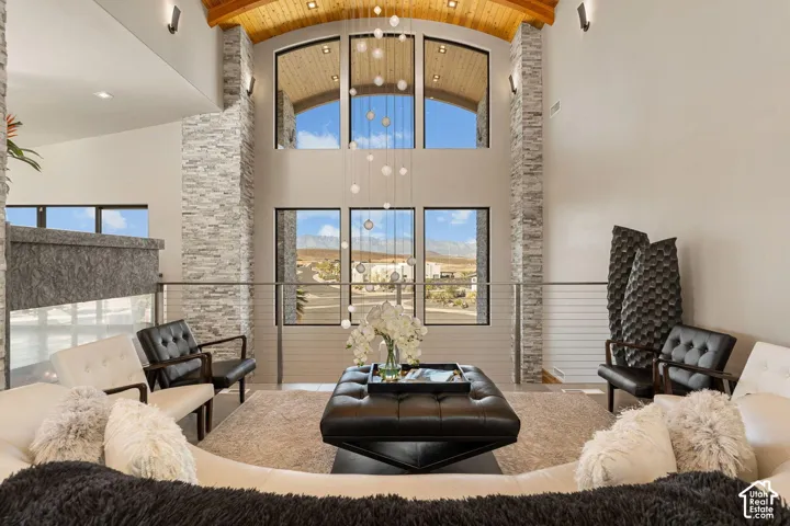 Two-story living area featuring stacked stone accent walls, a vaulted wood-paneled ceiling, and large windows with arched transoms