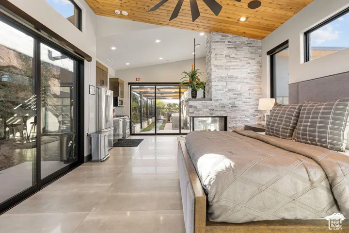 Vaulted ceiling with wood-finish planks, stone-clad fireplace, built-in recessed lighting, and large format tile flooring