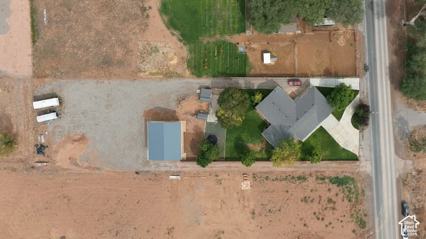 Gabled roofline, expansive gravel lot, standalone outbuilding, paved driveway, and established trees