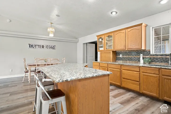 Kitchen with a granite-topped island, wood-finish cabinetry, and a patterned tile backsplash