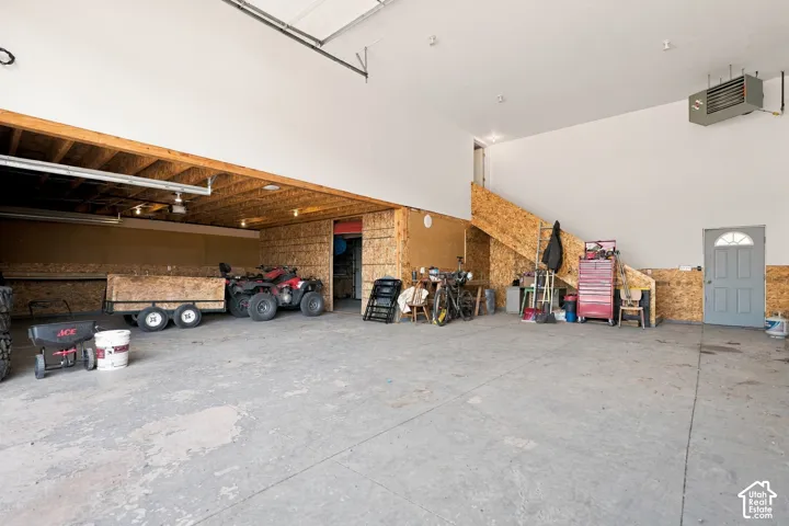 Expansive concrete flooring, high ceilings, exposed wood beam framing, and an overhead heater