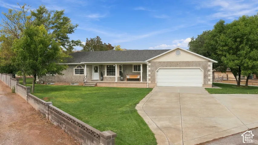 Brick and siding exterior with a covered porch, an attached two-car garage, a concrete driveway, and a manicured lawn