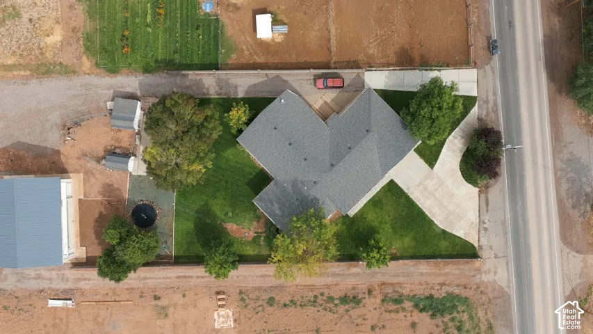 Property featuring a gray shingle roof, concrete driveway, attached garage, and a expansive lawn with mature trees