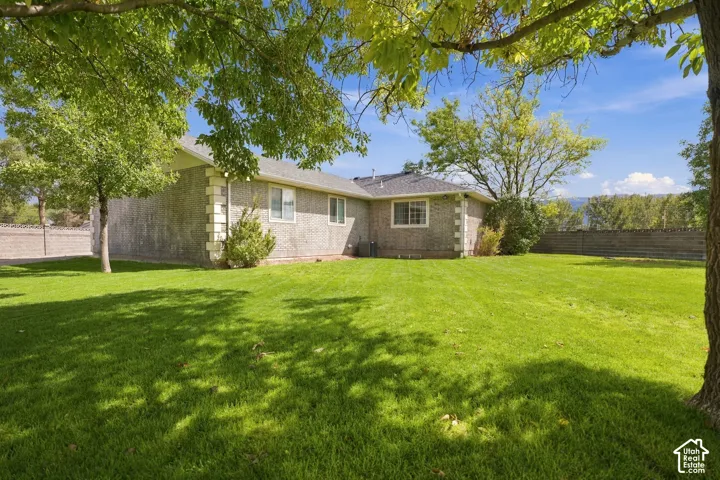 Expansive green lawn, mature trees, brick exterior, and a solid perimeter wall