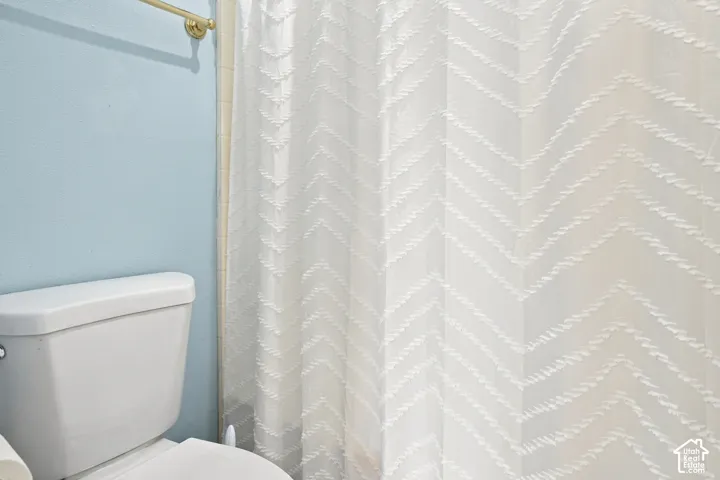 White toilet with a gold-finish towel bar and light blue wall