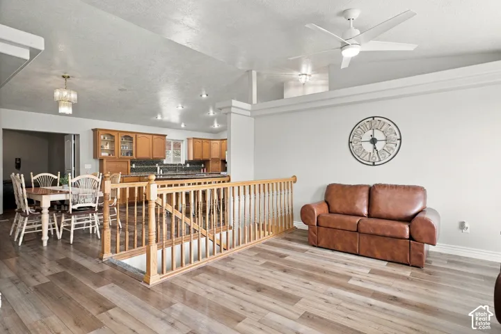 Open-concept living area featuring wood-finish flooring, a wood banister, and recessed lighting